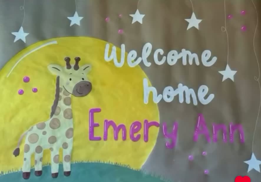 Welcome home Emery Ann banner with a hand-painted giraffe, moon, and stars